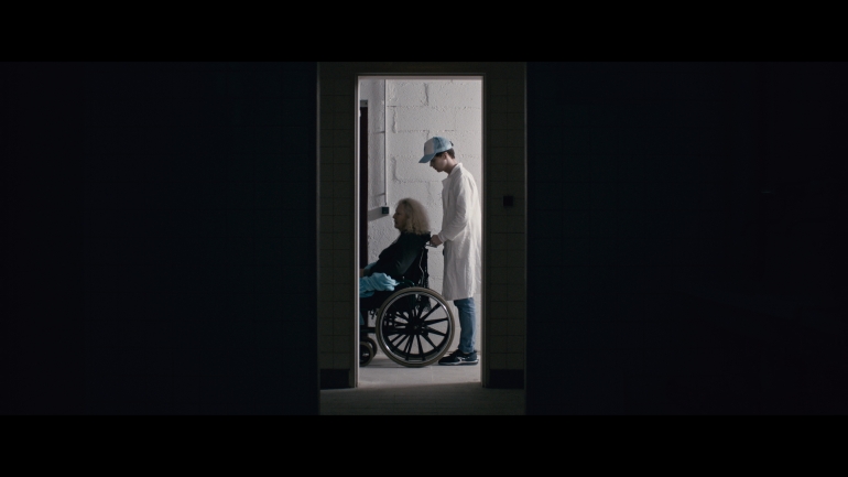 two persons are standing motionless in a doorway frame